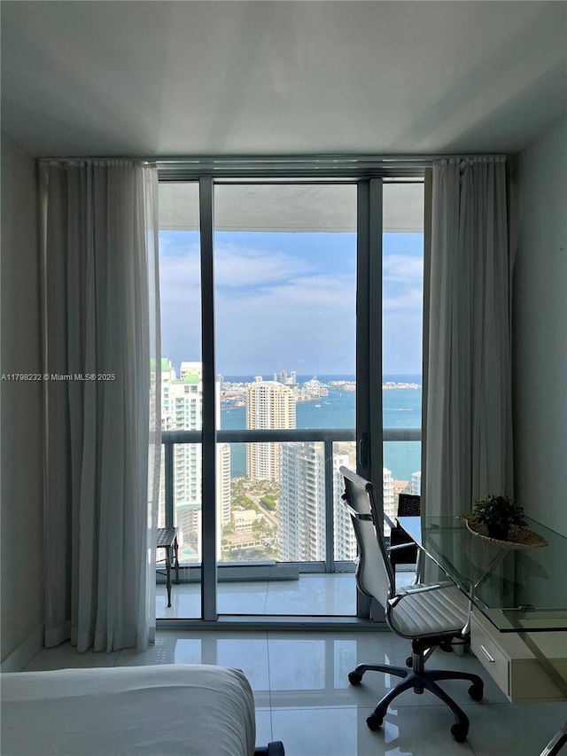 bedroom featuring a city view, multiple windows, a desk, floor to ceiling windows, and a water view
