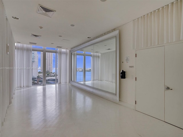 unfurnished room featuring expansive windows, healthy amount of natural light, and a water view