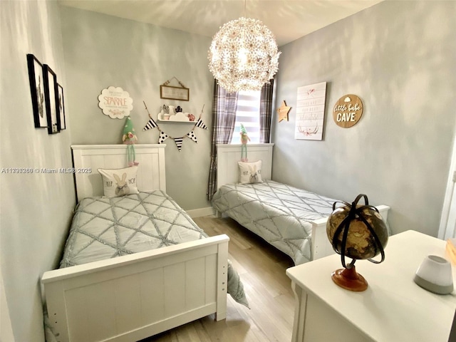 bedroom featuring a chandelier, light wood finished floors, and baseboards