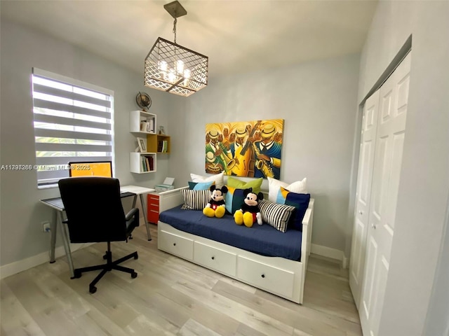 bedroom featuring light wood-style floors, a chandelier, a closet, and baseboards