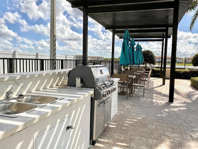 view of patio / terrace with area for grilling, fence, a sink, and outdoor dining area