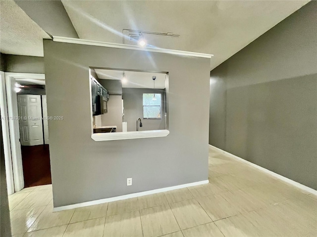 spare room with light tile patterned floors, rail lighting, baseboards, and a sink