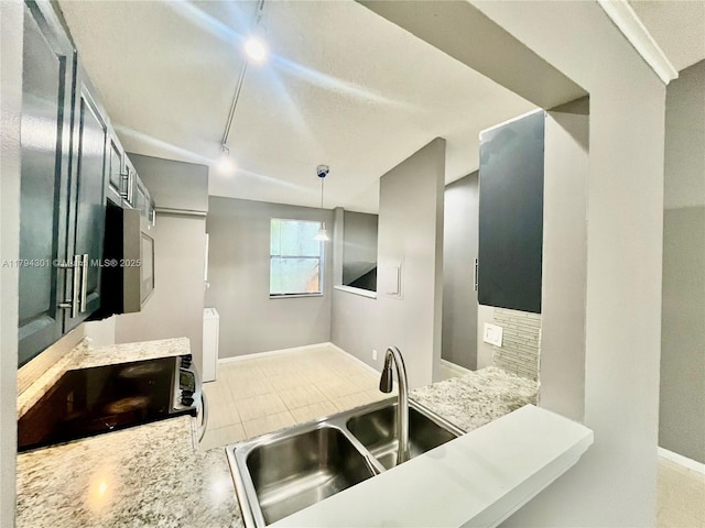 kitchen with a sink, baseboards, hanging light fixtures, track lighting, and radiator