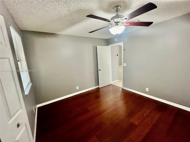 unfurnished bedroom featuring wood finished floors, a textured ceiling, baseboards, and a ceiling fan