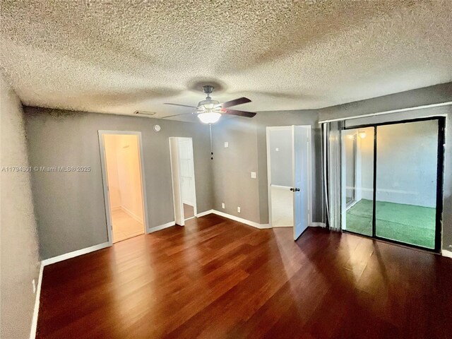 unfurnished room with dark wood-type flooring, a ceiling fan, baseboards, and a textured ceiling