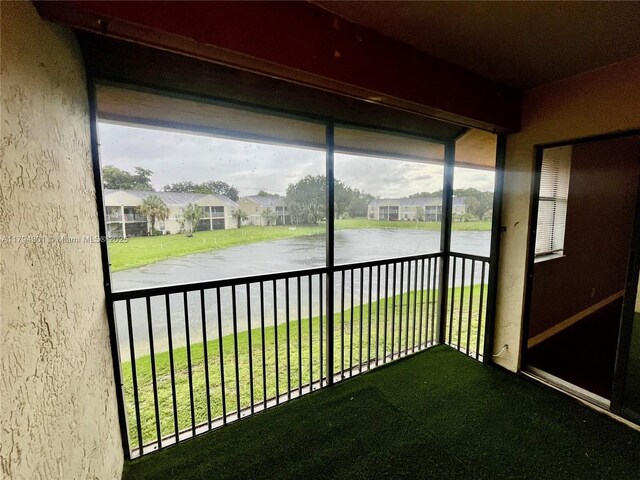 unfurnished sunroom featuring a water view and a residential view