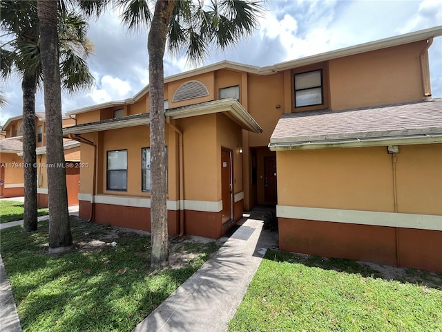 view of front of home with stucco siding and a front lawn