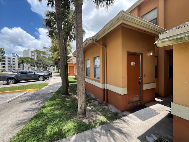 view of home's exterior with stucco siding and uncovered parking
