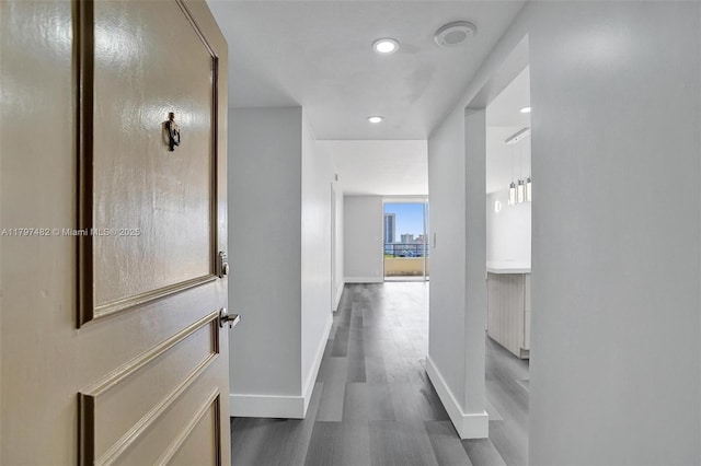corridor featuring baseboards, dark wood-type flooring, and recessed lighting