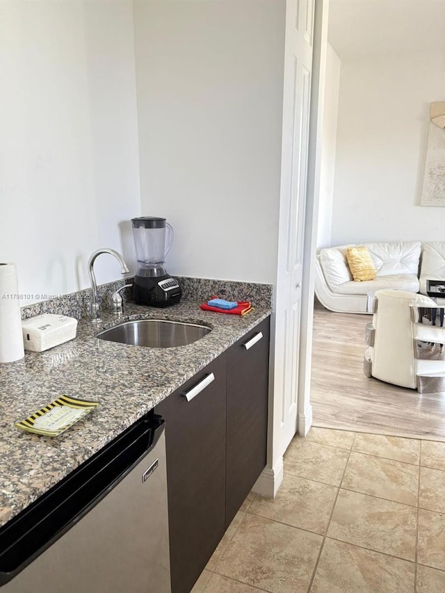 kitchen with dishwasher, a sink, and dark stone counters