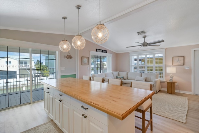 kitchen featuring light wood-type flooring, open floor plan, lofted ceiling, ceiling fan, and crown molding