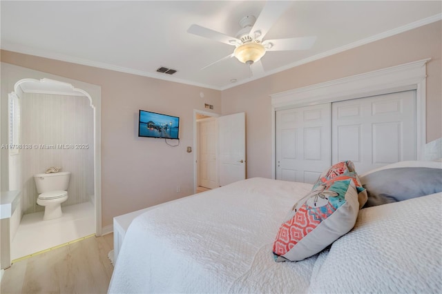 bedroom featuring ornamental molding, light wood-style floors, a closet, ceiling fan, and ensuite bathroom