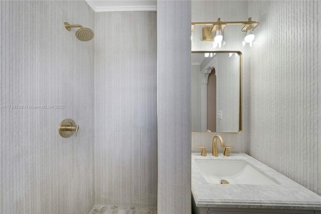 full bath featuring a tile shower, ornamental molding, and vanity