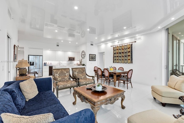 living area featuring a towering ceiling, recessed lighting, and light tile patterned floors