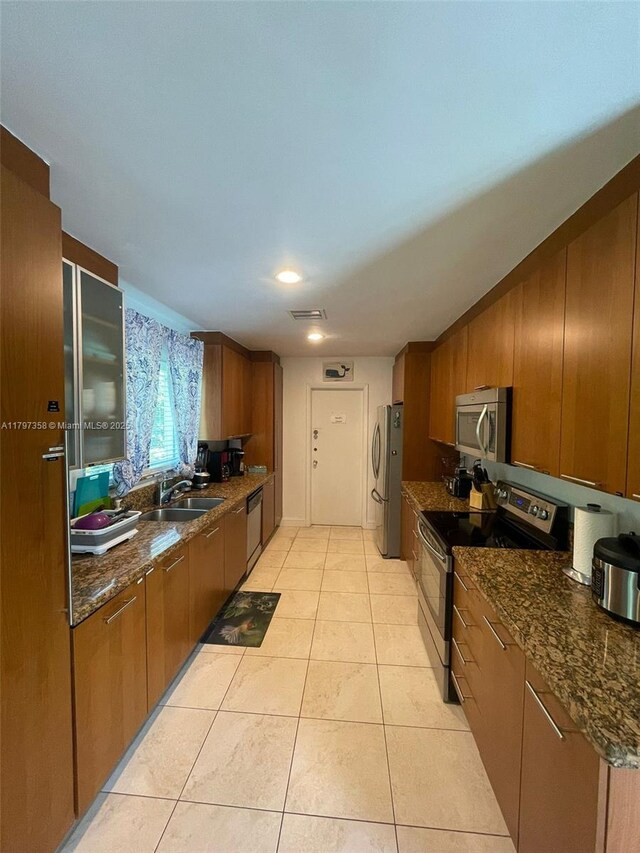 4410 N Buchanan St, Hollywood, FL 33021 - kitchen with stainless steel appliances, light tile patterned floors, a sink, brown cabinets, and dark stone counters