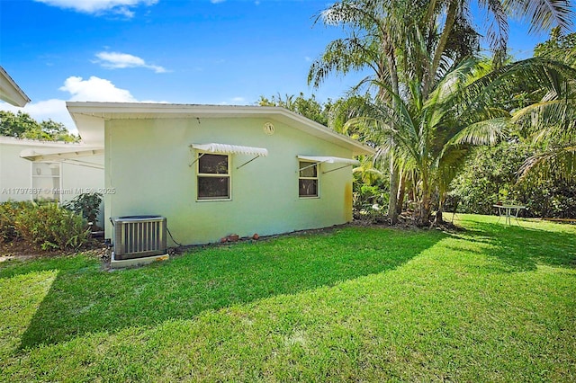 view of home's exterior featuring cooling unit, a lawn, and stucco siding