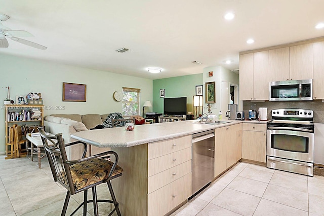 602 S Caloosahatchee Ave, Jupiter, FL 33458 - kitchen featuring appliances with stainless steel finishes, open floor plan, a peninsula, light brown cabinetry, and a breakfast bar area