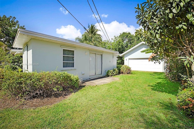 rear view of house with stucco siding, a lawn, and an outbuilding