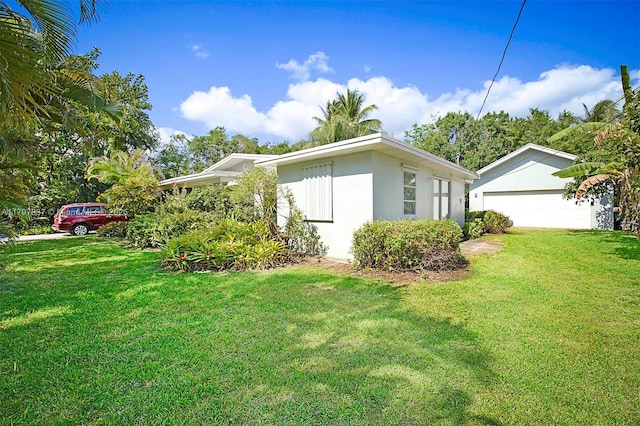 view of side of property with stucco siding, a garage, and a yard
