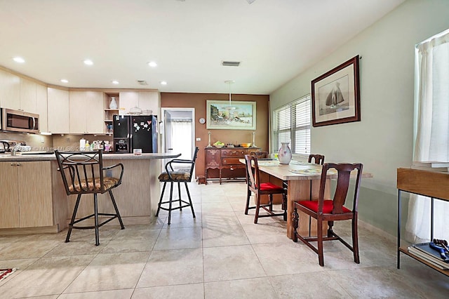 602 S Caloosahatchee Ave, Jupiter, FL 33458 - kitchen featuring black refrigerator with ice dispenser, stainless steel microwave, open shelves, a kitchen bar, and a peninsula