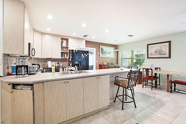 602 S Caloosahatchee Ave, Jupiter, FL 33458 - kitchen with black refrigerator with ice dispenser, a peninsula, stainless steel microwave, open shelves, and light countertops