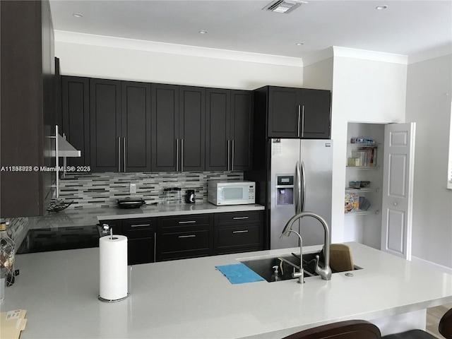 1010 NE 36th Ave, Homestead, FL 33033 - kitchen with stainless steel fridge with ice dispenser, white microwave, dark cabinetry, a sink, and ornamental molding