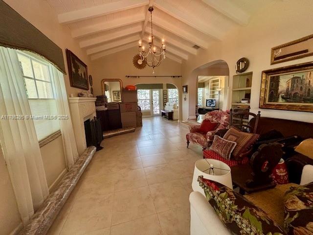 living area featuring arched walkways, a fireplace, a chandelier, and light tile patterned floors
