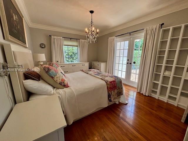 bedroom with ornamental molding, access to exterior, dark wood-style flooring, a chandelier, and french doors