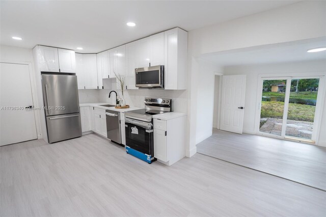 3531 NW 26th St, Lauderdale Lakes, FL 33311 - kitchen featuring appliances with stainless steel finishes, a sink, light wood-type flooring, light countertops, and white cabinetry