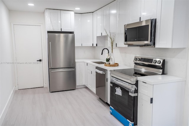 3531 NW 26th St, Lauderdale Lakes, FL 33311 - kitchen featuring stainless steel appliances, a sink, white cabinetry, light wood-style floors, and light countertops