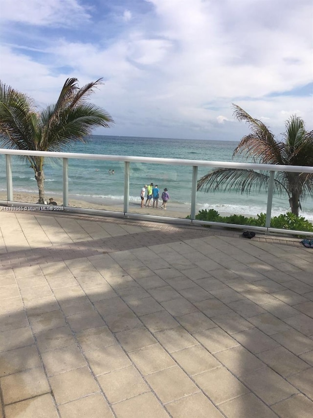 view of patio / terrace with a balcony and view of water and beach