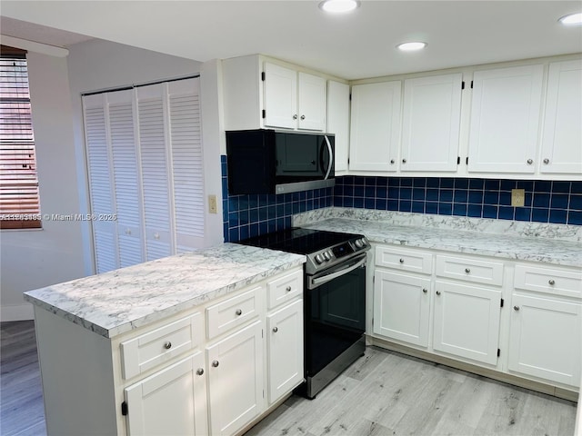 kitchen with electric range oven, black microwave, light wood-type flooring, tasteful backsplash, and white cabinetry