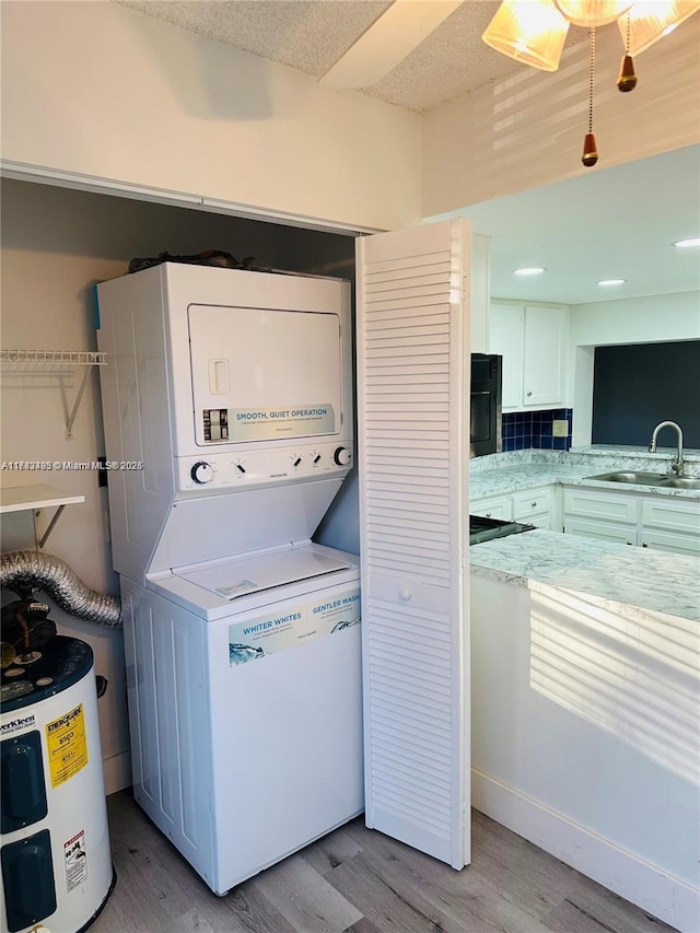 laundry area featuring stacked washing machine and dryer, light wood-style flooring, and electric water heater