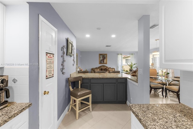 kitchen featuring light stone counters, baseboards, light tile patterned floors, recessed lighting, and open floor plan