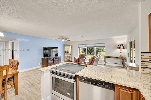 14030 Nesting Way Unit D, Delray Beach, FL 33484 - kitchen with appliances with stainless steel finishes, open floor plan, a textured ceiling, ceiling fan, and light stone counters