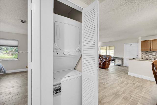 14030 Nesting Way Unit D, Delray Beach, FL 33484 - laundry room with stacked washer / dryer, a textured ceiling, healthy amount of natural light, and light wood finished floors