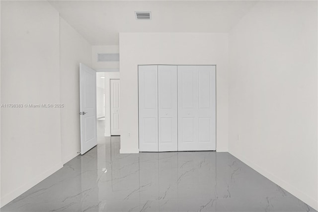 unfurnished bedroom featuring marble tiled flooring, baseboards, and a closet