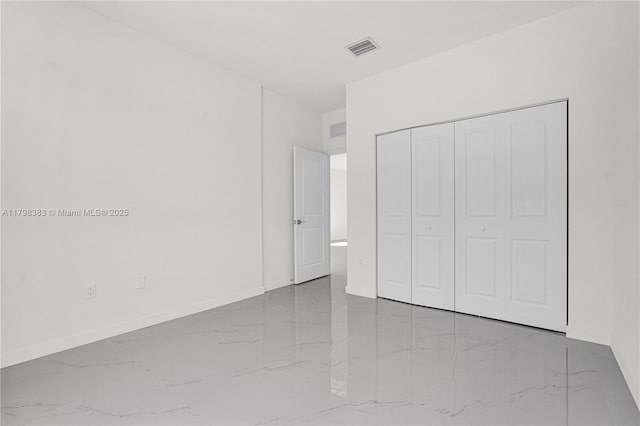 unfurnished bedroom featuring marble finish floors, baseboards, and a closet