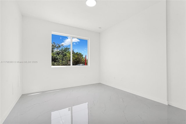 empty room featuring marble tiled flooring and baseboards