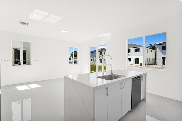 kitchen featuring a sink, light marble finish flooring, dishwashing machine, a center island with sink, and modern cabinets