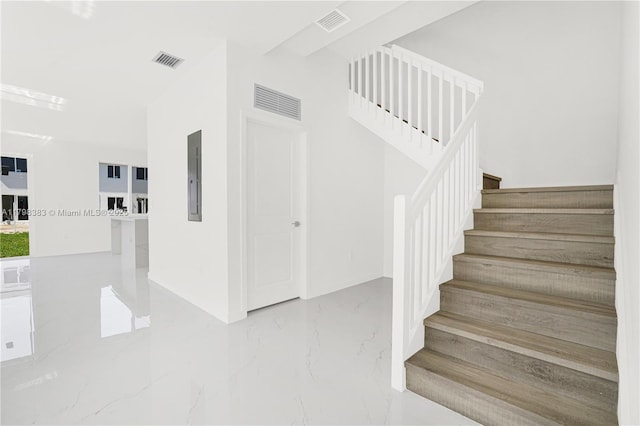 stairway with marble tiled floors, electric panel, and baseboards