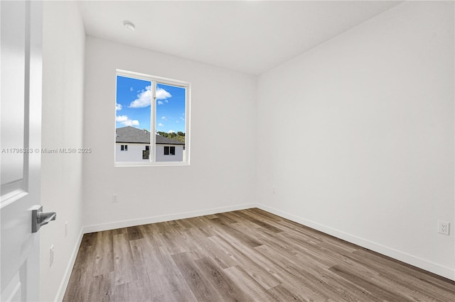 spare room featuring wood finished floors, baseboards, and a smoke detector