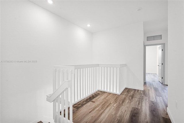 hallway with an upstairs landing, wood finished floors, recessed lighting, and baseboards