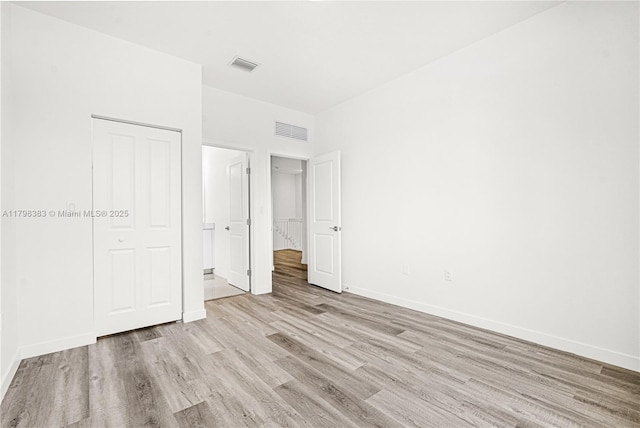 unfurnished bedroom with light wood finished floors, baseboards, and a closet