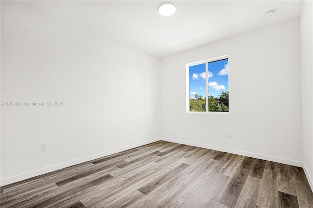 spare room featuring wood finished floors, baseboards, and a smoke detector
