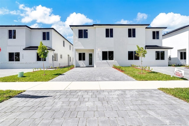 modern farmhouse style home featuring decorative driveway and stucco siding