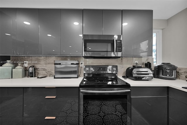 kitchen featuring stainless steel microwave, black / electric stove, modern cabinets, and tasteful backsplash
