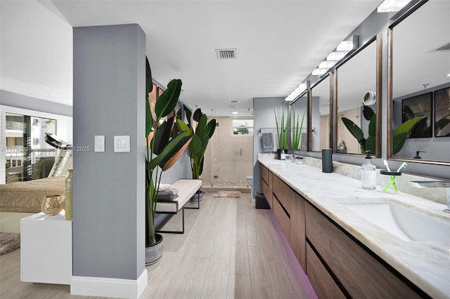 bathroom with a shower stall, wood finished floors, double vanity, and toilet