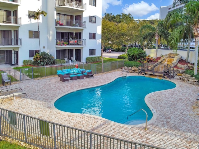 community pool with an outdoor living space, fence, and a patio