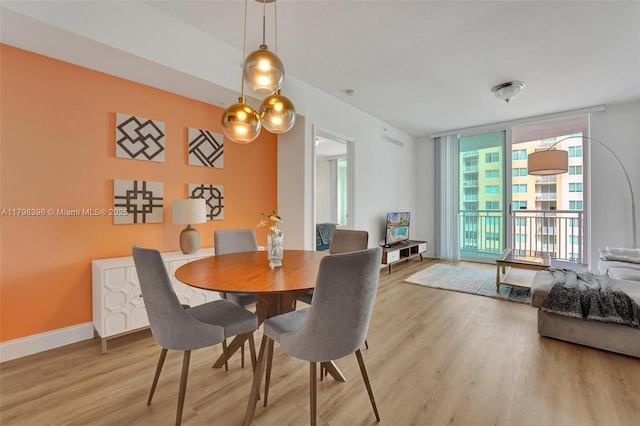 dining room featuring expansive windows, light wood-type flooring, and baseboards